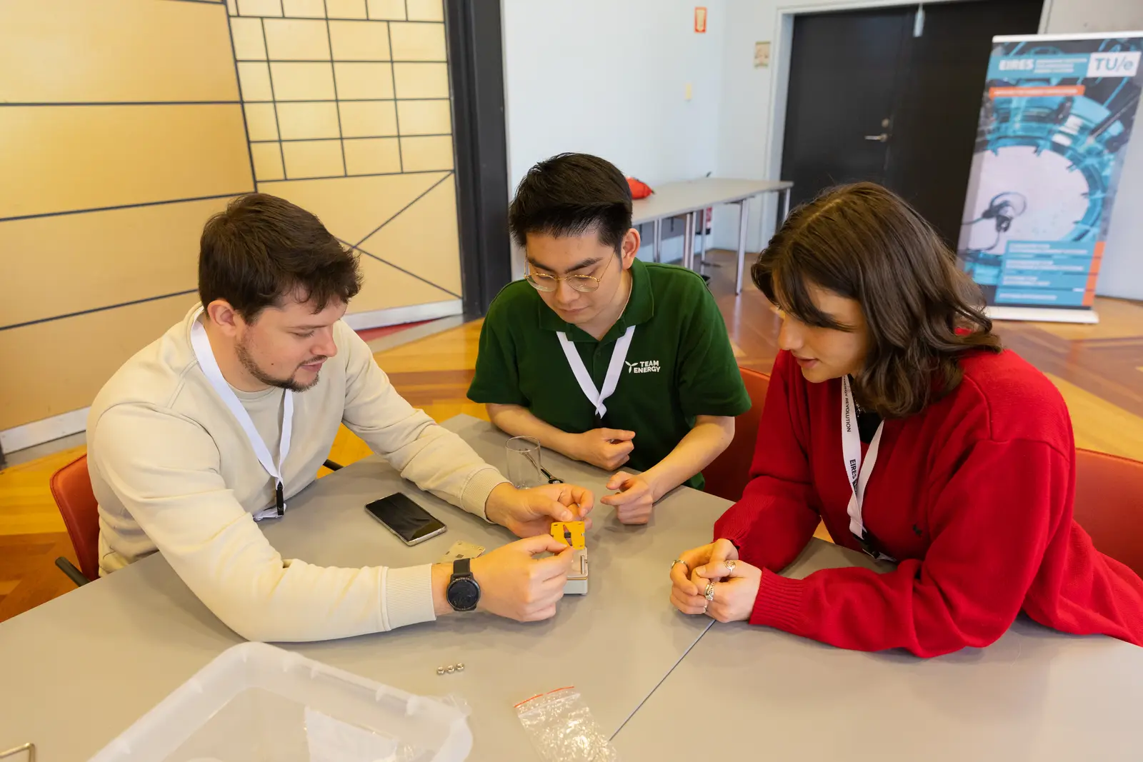 Three people seated at a table assembling a flow cell kit